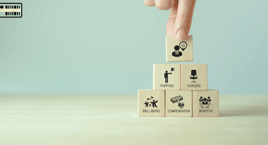 A hand places a wooden block with a clock and person icon atop a pyramid of blocks labeled purpose, careers, wellbeing, compensation, and benefits.